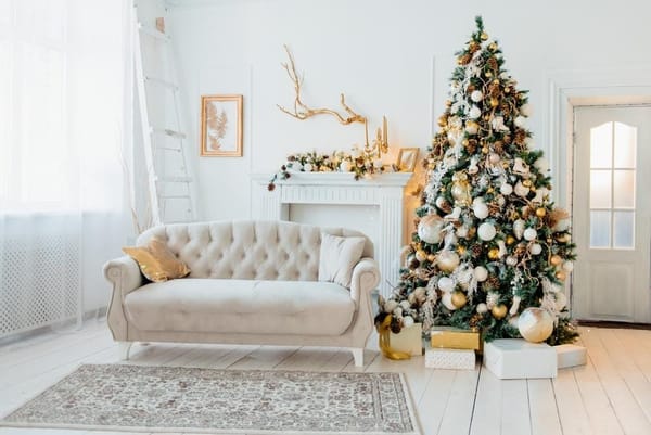Weißes Weihnachtszimmer mit einem mit goldenem Spielzeug geschmückten Weihnachtsbaum